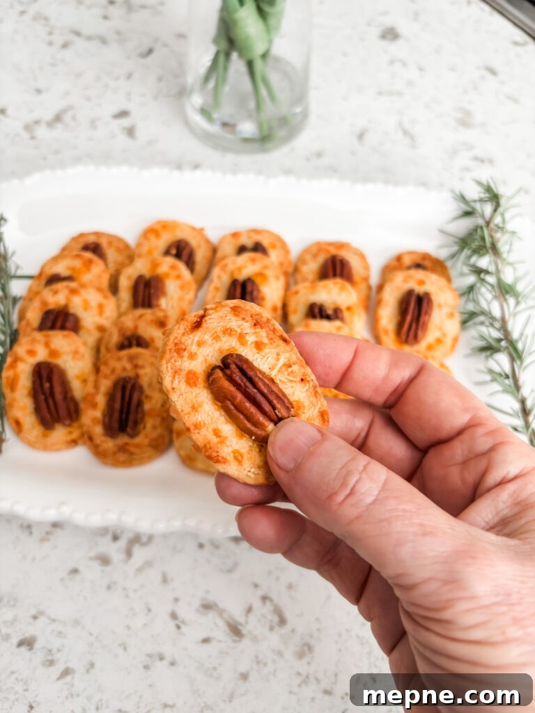 Savory Southern Pecan Cheese Wafers Recipe 2 Marie holding up one of the Southern Style Cheese Wafers