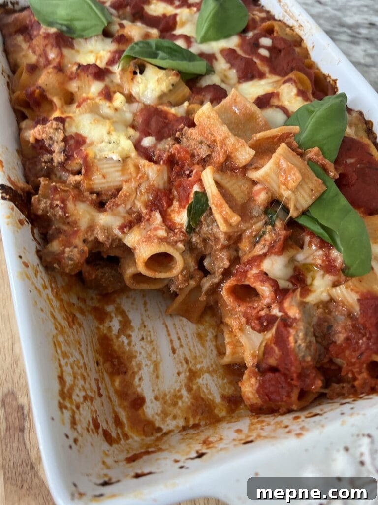 Baked Rigatoni al forno in baking dish with one slice cut out.