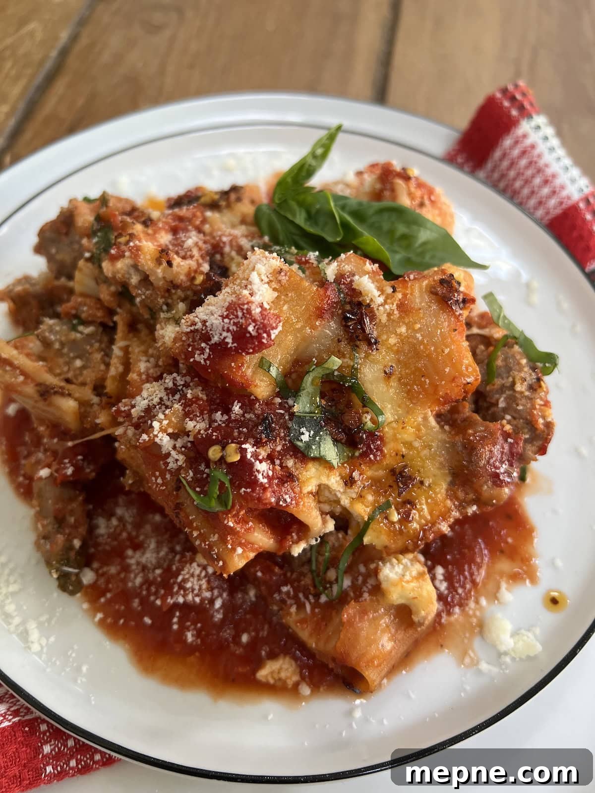 Close-up of a portion of pasta al forno in white dish with basil garnish.