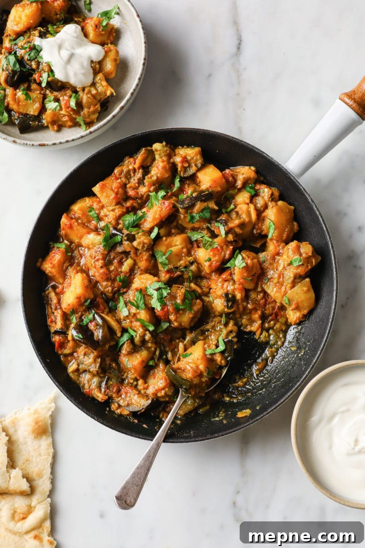 Aloo Baingan: Indian Eggplant and Potato Curry 2 Aloo Baingan in a skillet with naan and yogurt on the side