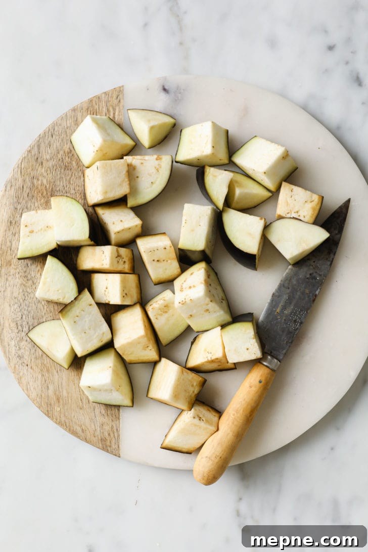 Aloo Baingan: Indian Eggplant and Potato Curry 5 Chopped Eggplant/Aubergine on a marbled surface along with a knife