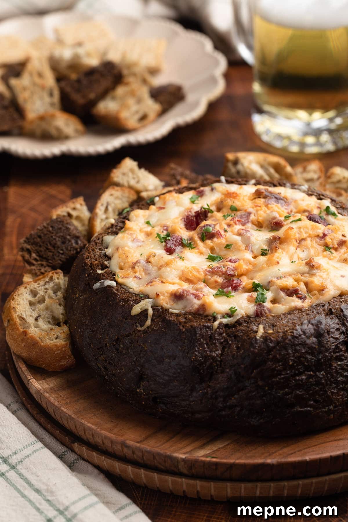 baked reuben dip in a pumpernickel bread bowl on a wood platter with chunks of toasted bread