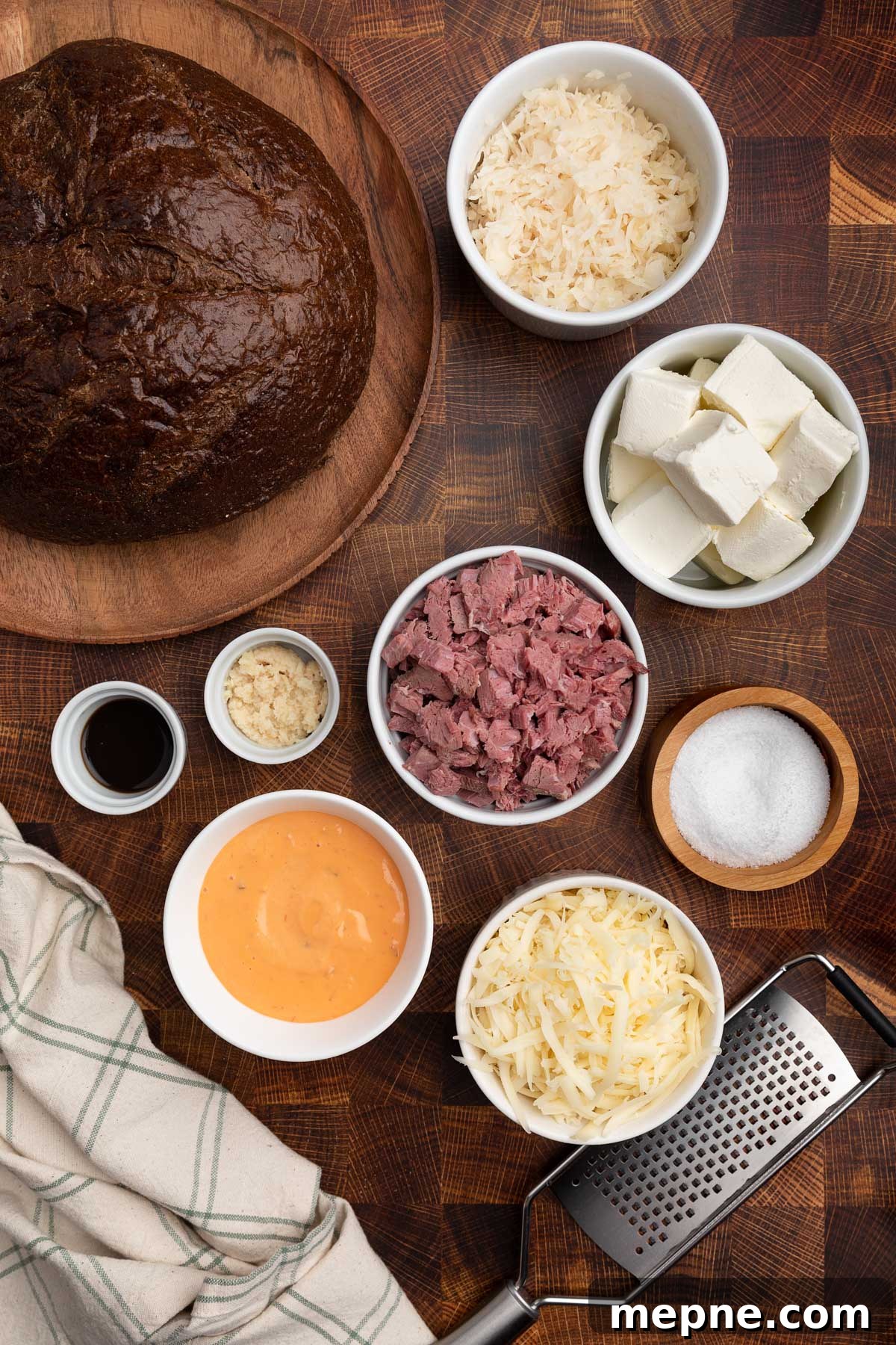 overhead photo of ingredients needed to make reuben dip in bowls on a wood butcher block board 