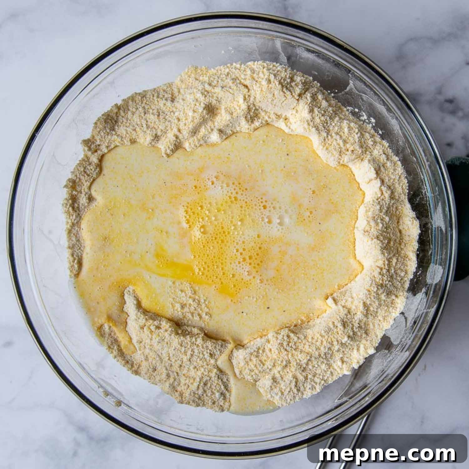 Moist Gluten Free Corn Muffins Recipe 4 the liquid ingredients being stirred into the dry corn muffin mixture.
