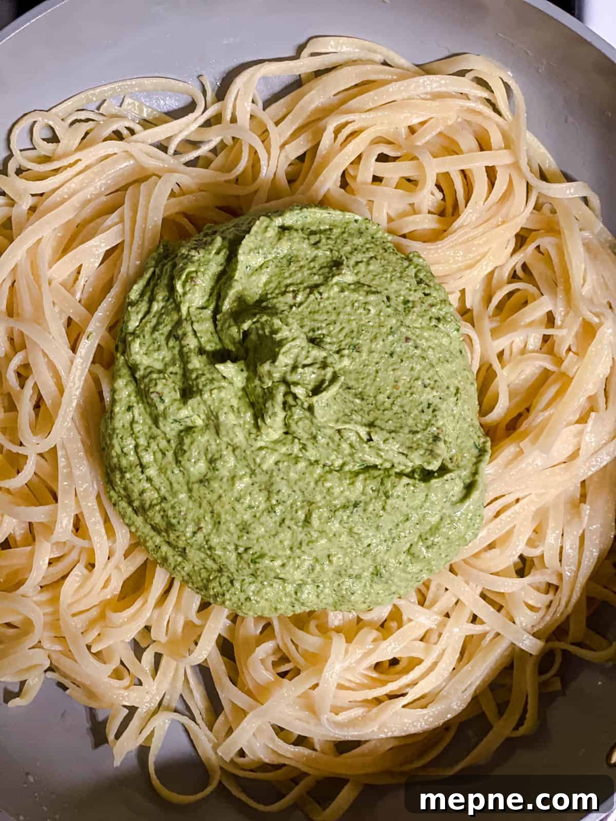 Creamy Avocado Pesto Pasta Recipe 7 process shot of avocado pesto being added to noodles
