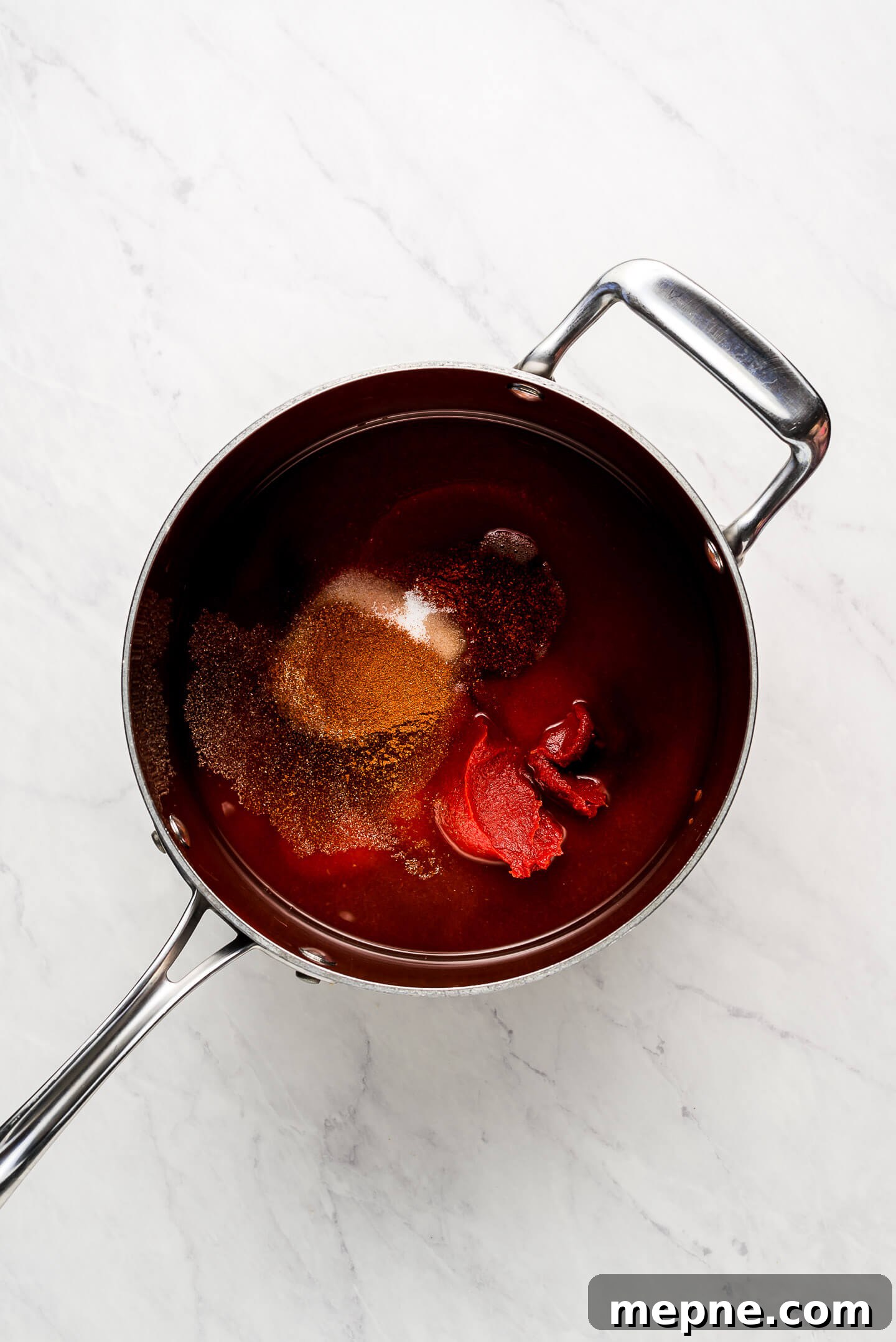 A pot of tomato sauce, paste, and seasonings.