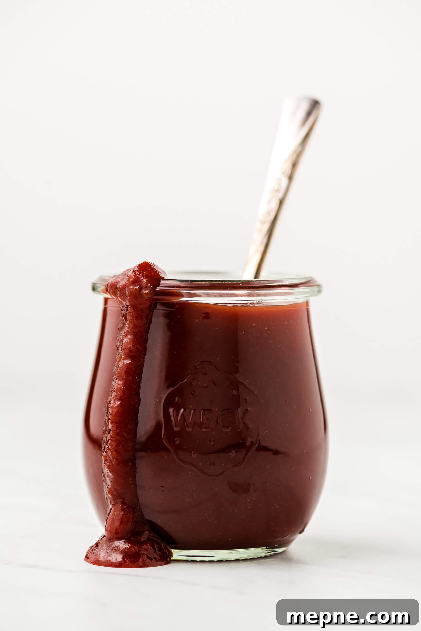 A jar of homemade barbecue sauce with some dripping down the side of the jar.