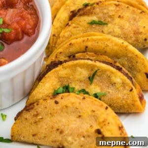 Air fried mini tacos served on a white plate with a side of salsa for dipping.