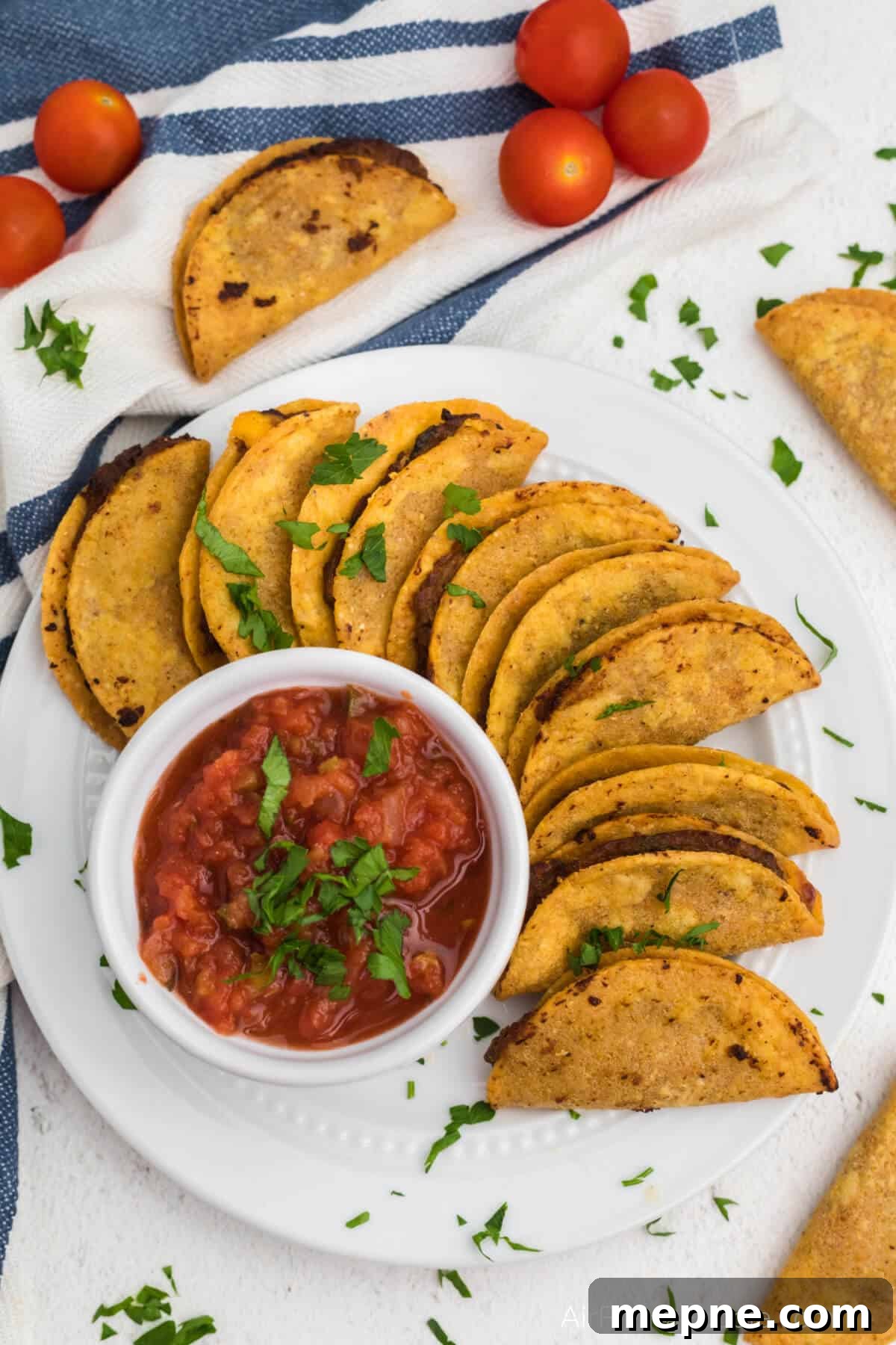 Air Fryer Frozen Mini Tacos: Crispy in Minutes 6 Overhead photo of mini tacos air fried and served on a white plate with salsa for dipping.