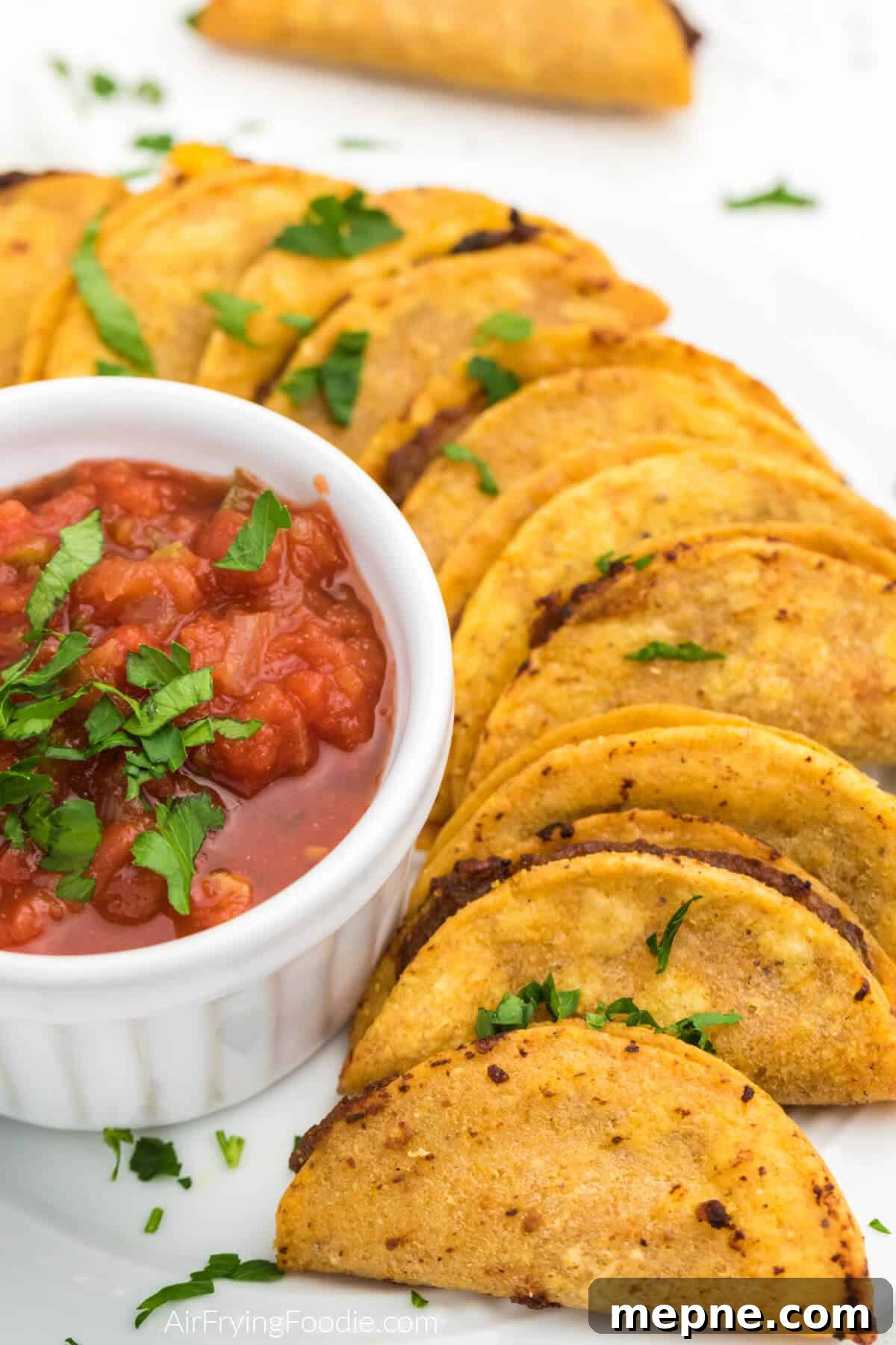 Air Fryer Frozen Mini Tacos: Crispy in Minutes 7 Air fried mini tacos on a white plate with salsa for dipping.