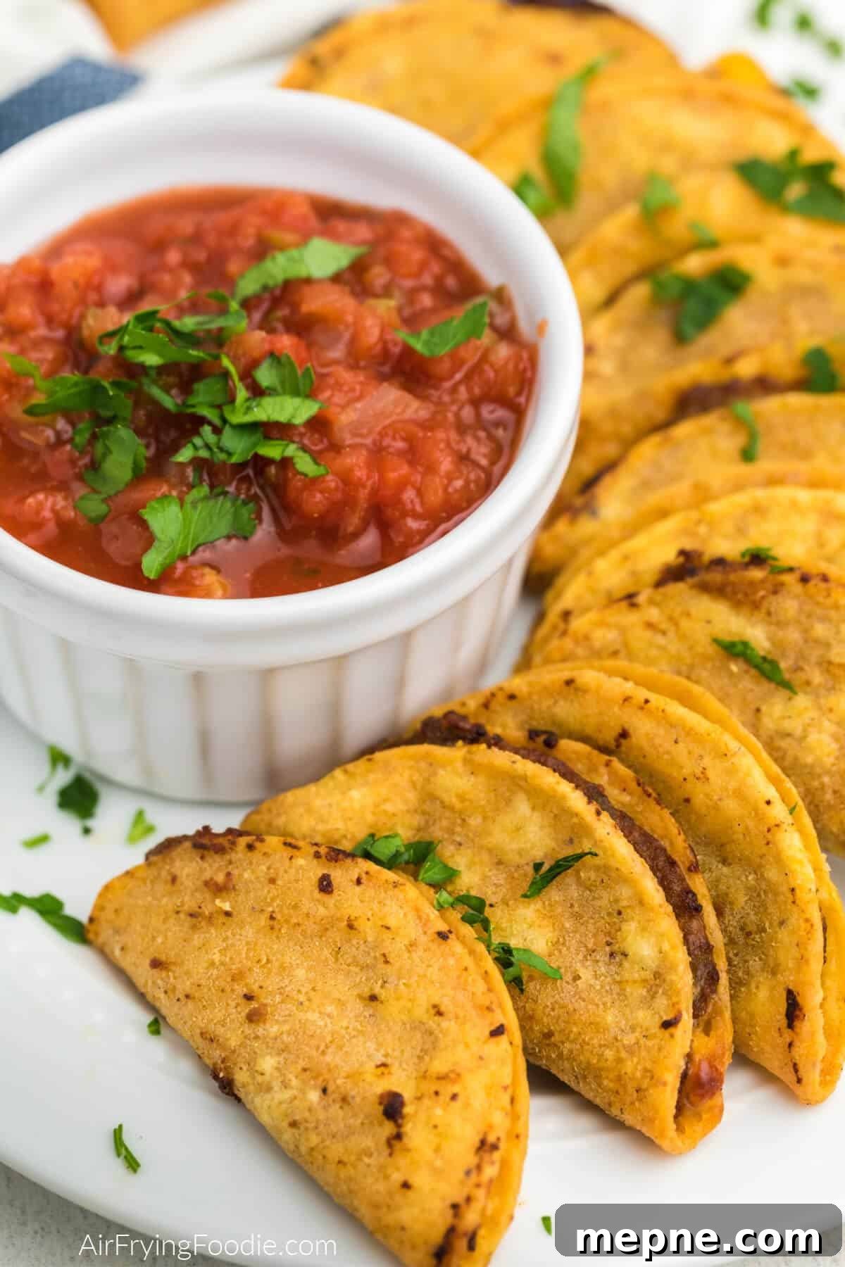 Air Fryer Frozen Mini Tacos: Crispy in Minutes 8 Plate full of air fried mini tacos with a bowl of salsa for dipping.