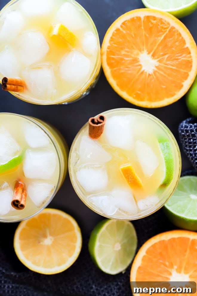 Spiced Rum Punch Recipe with Citrus and Warm Spices 5 image of big batch cocktail in glasses with citrus fruit halves