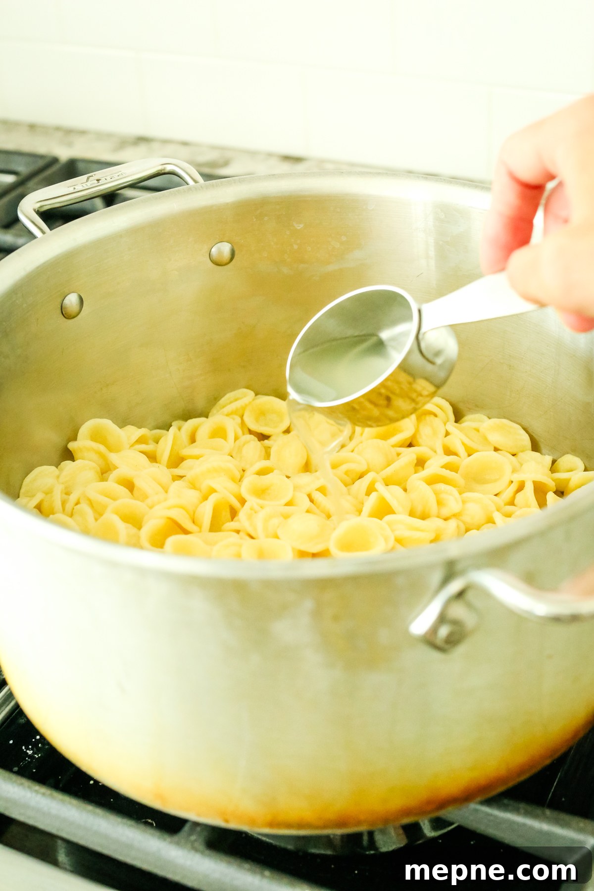 Orecchiette with Pesto, Asparagus and Spring Peas 5 adding pasta water to a pot of pasta