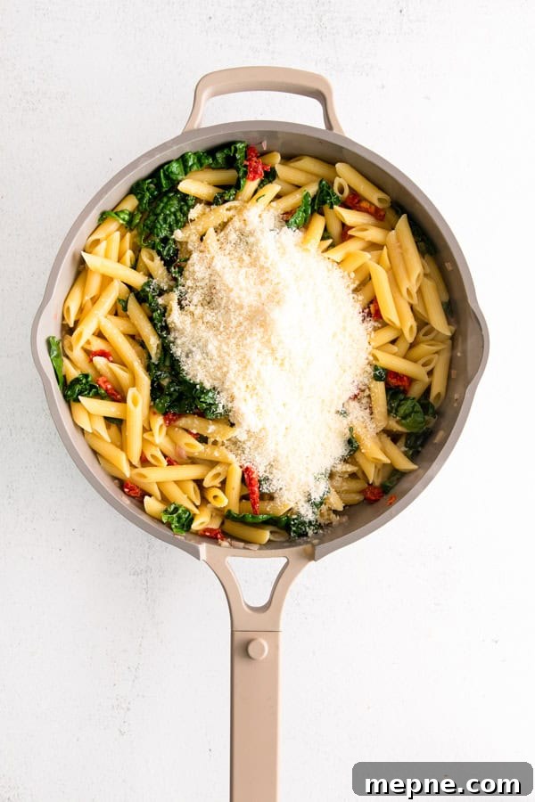 Sun-Dried Tomato and Kale Pasta Recipe 5 Pasta in a pan with Parmesan cheese.