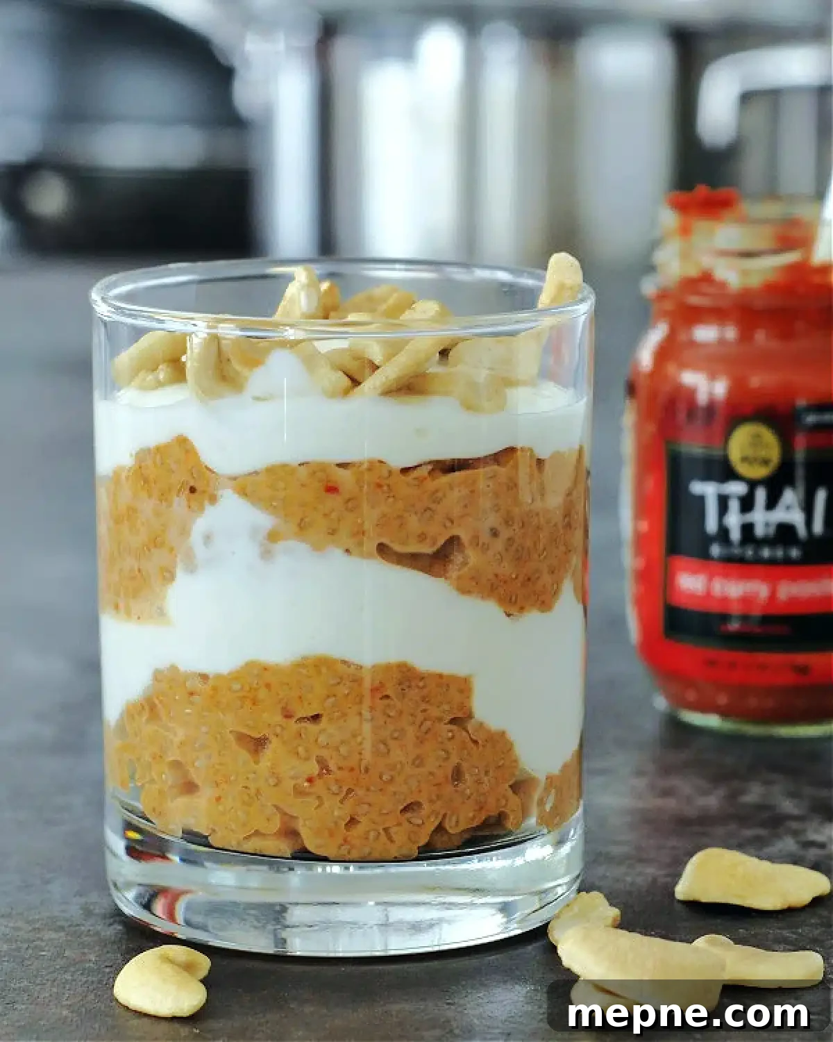 Savory Red Curry Chia Pudding @spabettie #glutenfree #lowcarb #vegan #dairyfree #recipe Red curry coconut chia pudding and cashew cream layered in a glass, red curry paste jar in background.
