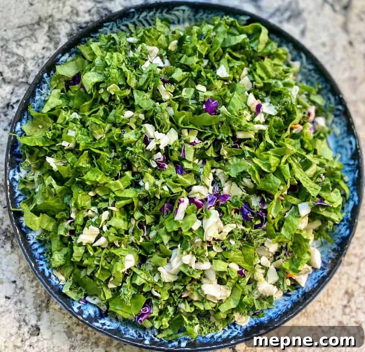 Asian Chopped Salad Recipe with Sesame Ginger Dressing 3 Kale, Romaine lettuce, and red and white cabbage chopped on a platter.