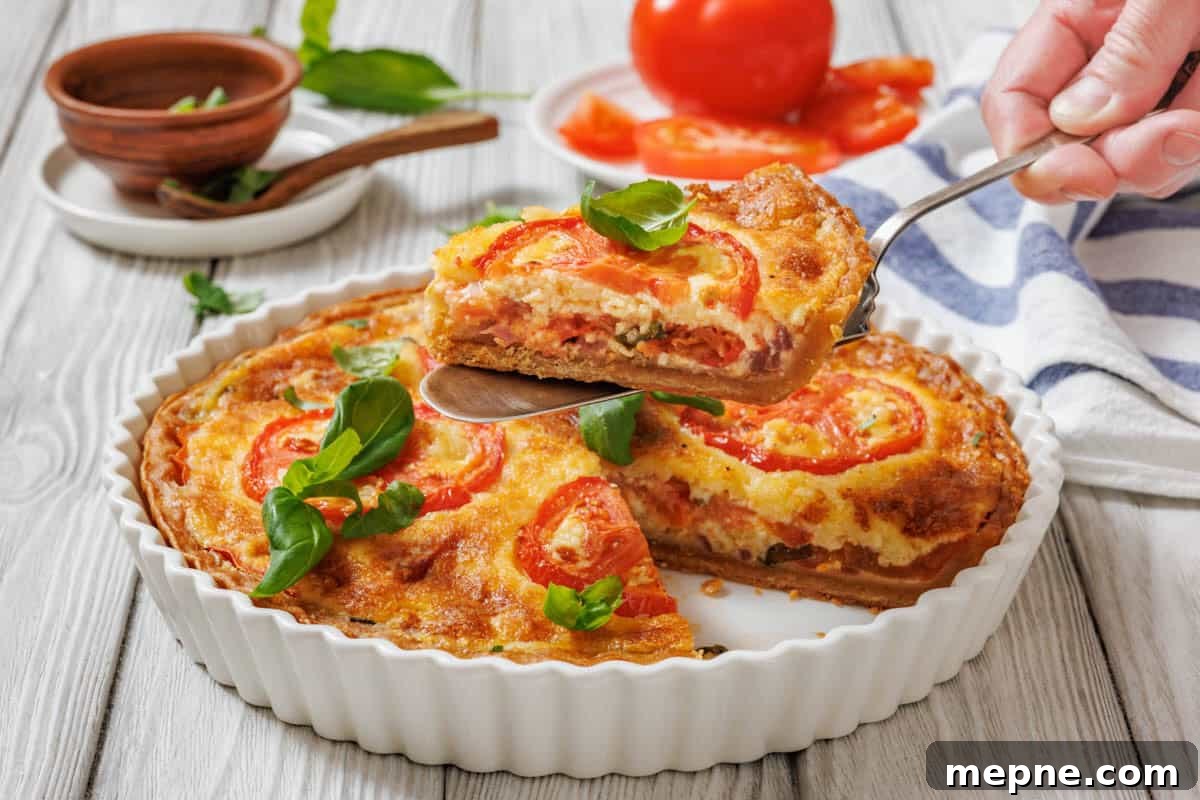 31 Southern Recipes That Belong in Your Dinner Rotation 12 A slice of tomato pie being lifted with a serving utensil from a white fluted dish. A whole tomato pie is visible in the dish, garnished with tomato slices and basil.