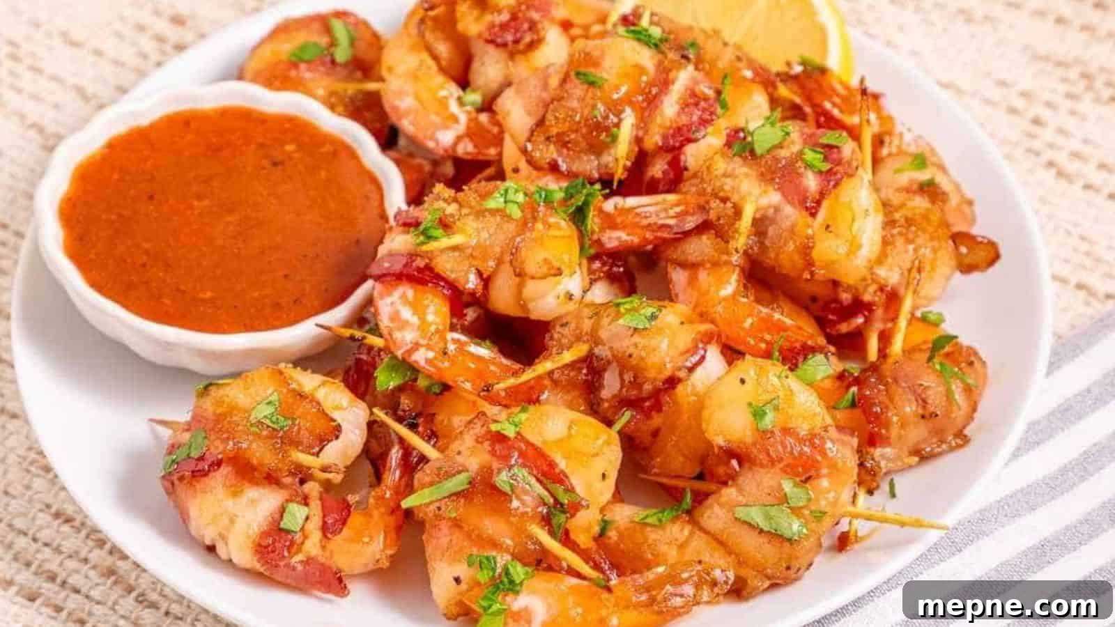 31 Southern Recipes That Belong in Your Dinner Rotation 17 A plate of bacon-wrapped shrimp garnished with chopped herbs, served with a small bowl of reddish dipping sauce and a lemon wedge.
