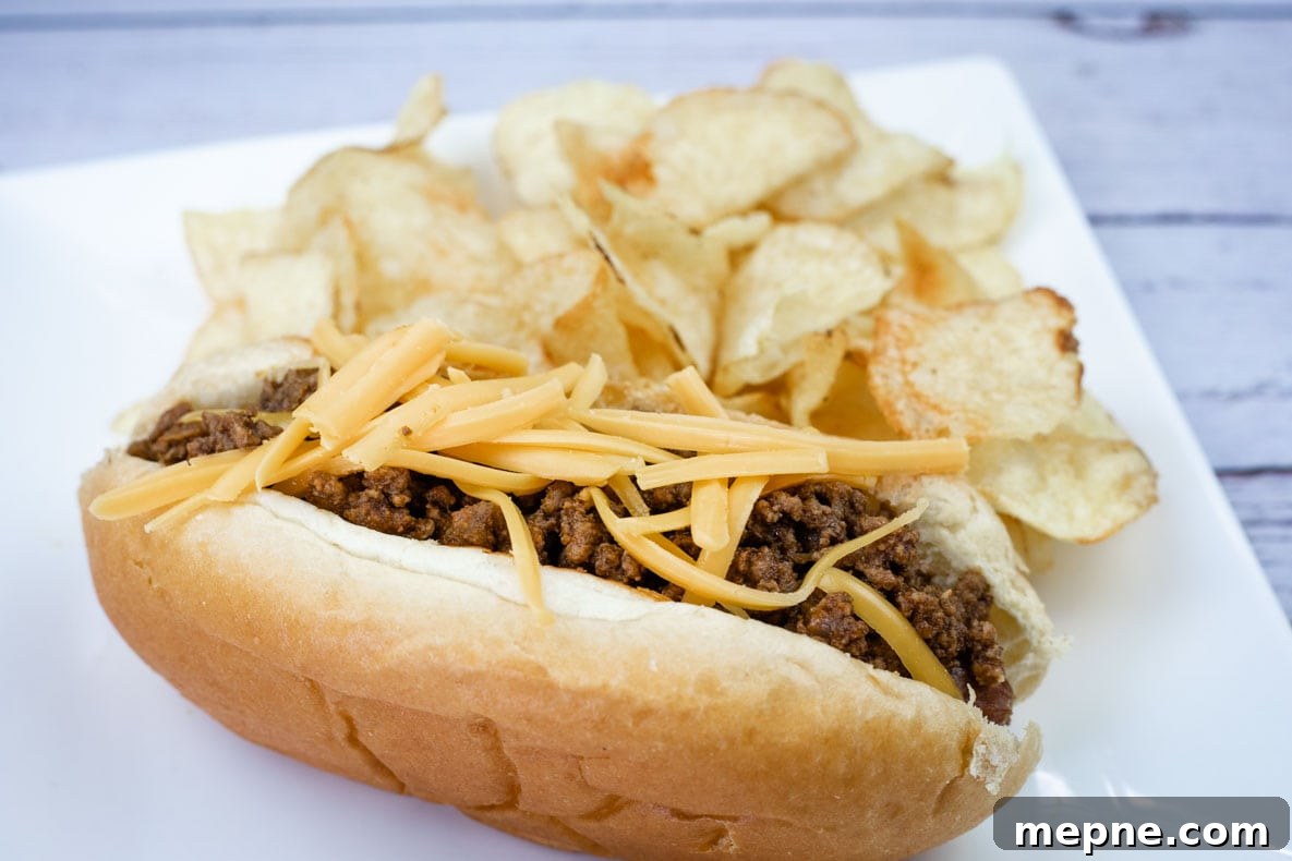 31 Southern Recipes That Belong in Your Dinner Rotation 29 A hot dog chili topped with shredded cheddar, served with potato chips on a white plate.