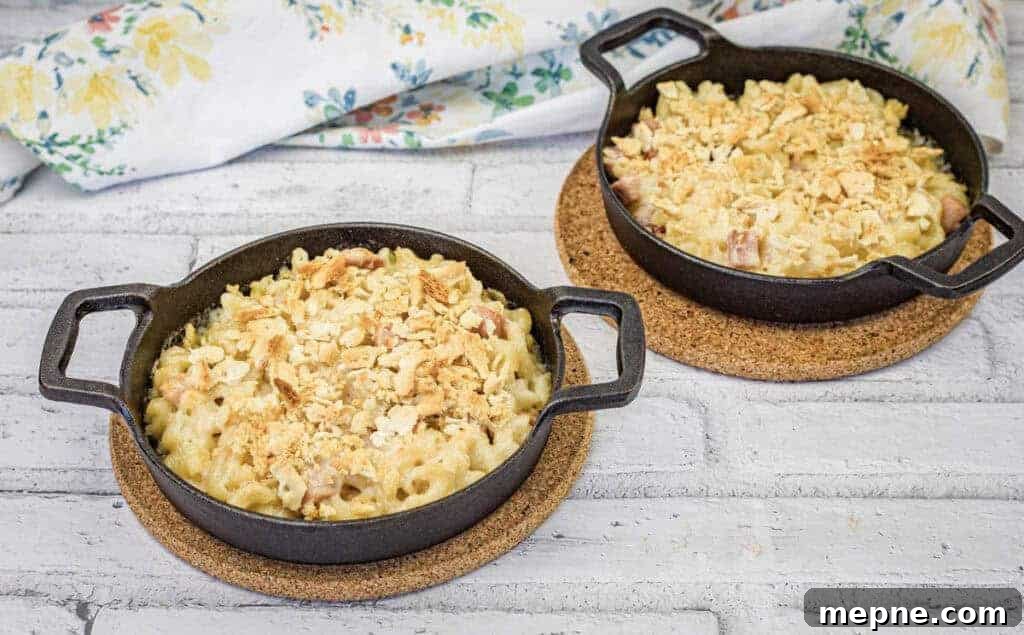 31 Southern Recipes That Belong in Your Dinner Rotation 4 Two black cast iron pans filled with mac and cheese sit on cork trivets on a white wooden surface.
