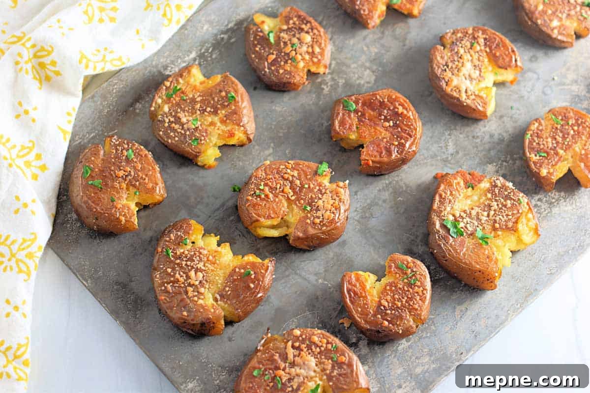 31 Southern Recipes That Belong in Your Dinner Rotation 5 A baking sheet with several smashed roasted potatoes, garnished with herbs and grated cheese, arranged in rows.