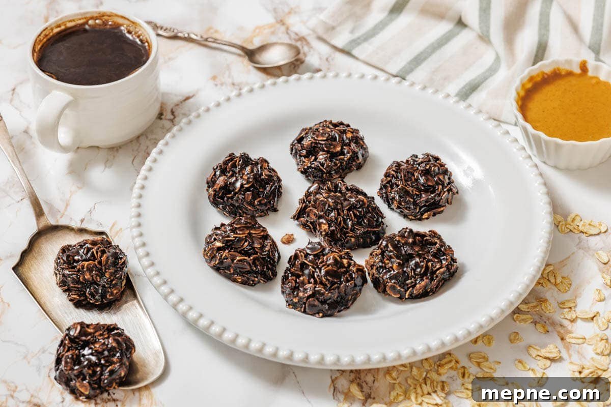31 Southern Recipes That Belong in Your Dinner Rotation 7 A white plate with seven Peanut Butter No-Bake Cookies on a marble surface, surrounded by a cup of coffee, a spoon, a bowl of nut butter, oats, and a striped cloth.