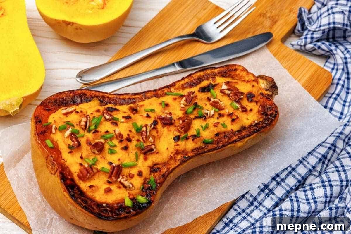 31 Southern Recipes That Belong in Your Dinner Rotation 9 A baked Butternut Squash Mash with Parmesan, garnished with chopped nuts and herbs, served on parchment paper, accompanied by a fork, knife, and a blue checkered cloth.