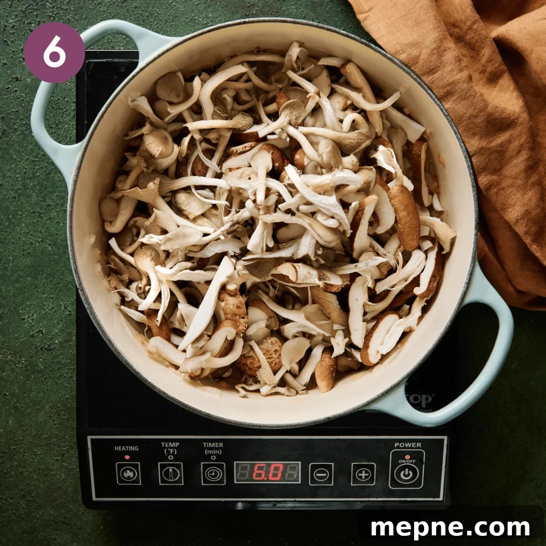 a big pile of sliced and torn mushrooms sitting in a light blue dutch oven.