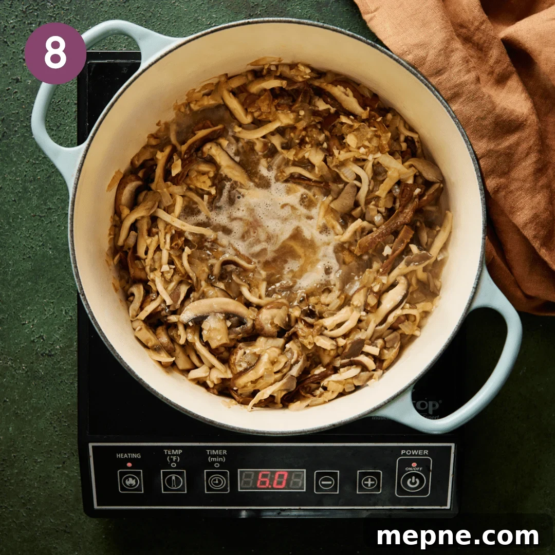 sliced mushrooms sautéing in a light blue dutch oven while white wine is deglazing the pan.