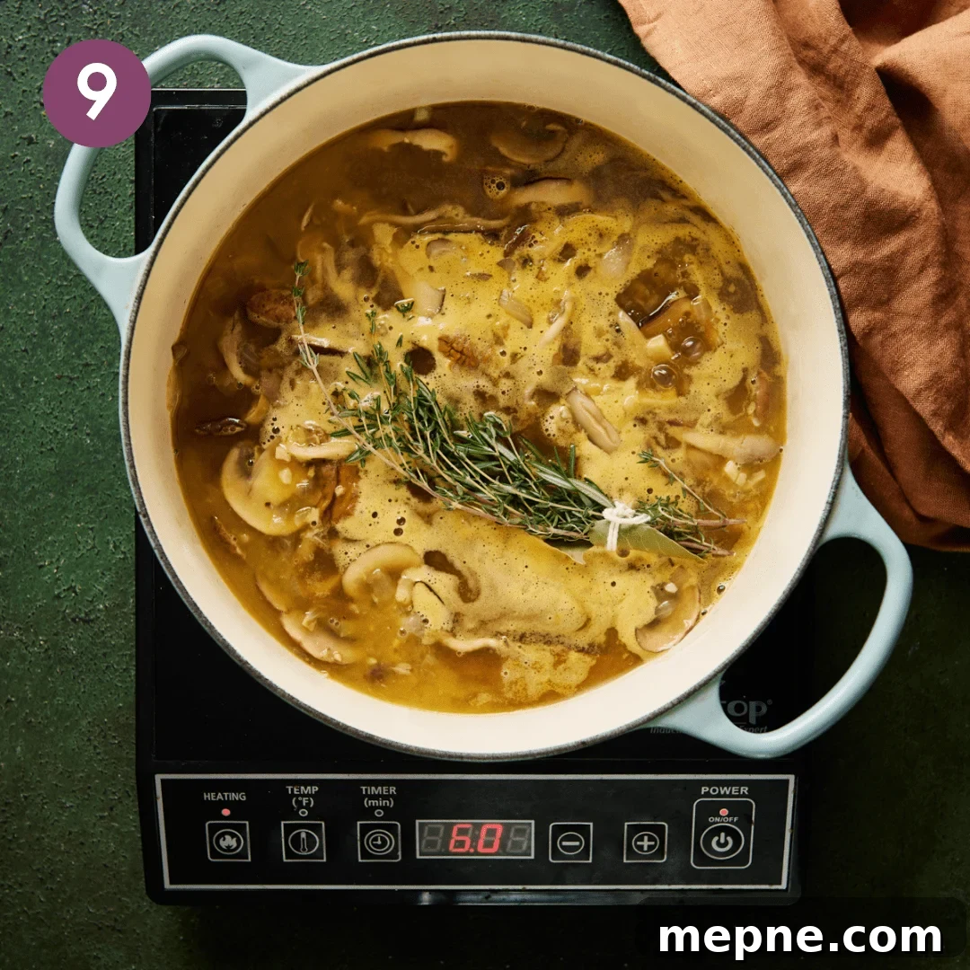 a mushroom soup coming to a simmer with a bouquet garni in the middle of the soup pot.