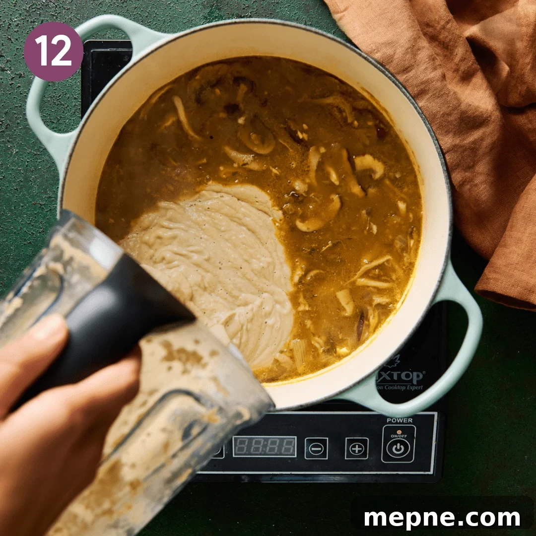 woman's hands pouring blended mushroom soup in a soup pot of mushroom soup.
