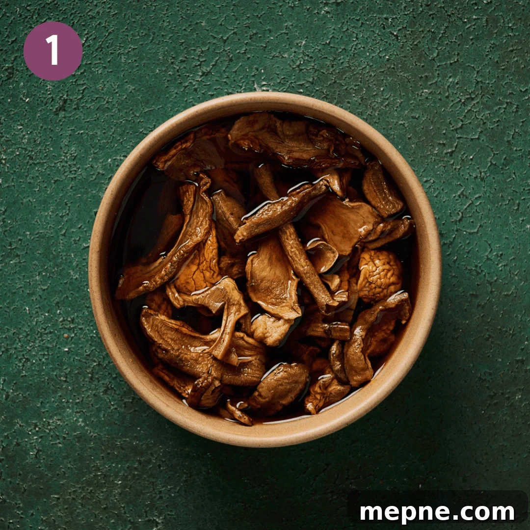 a tan bowl of dried mushrooms rehydrating in liquid for mushroom stock on a green surface.