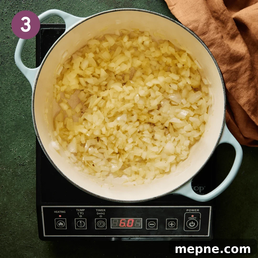 diced onions sauteeing in olive oil in a light blue dutch oven.