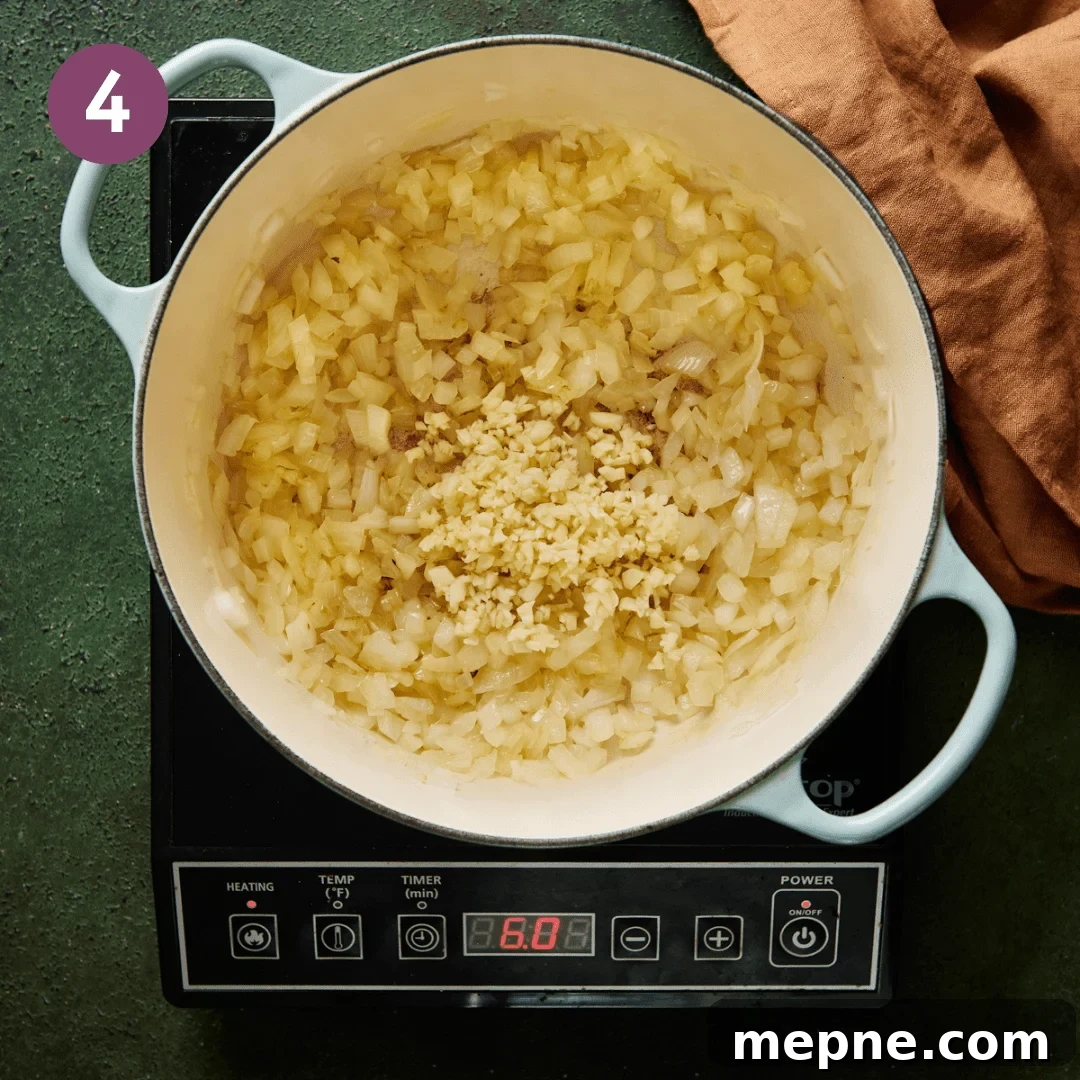 diced onions and minced garlic sauteeing in olive oil in a light blue dutch oven.
