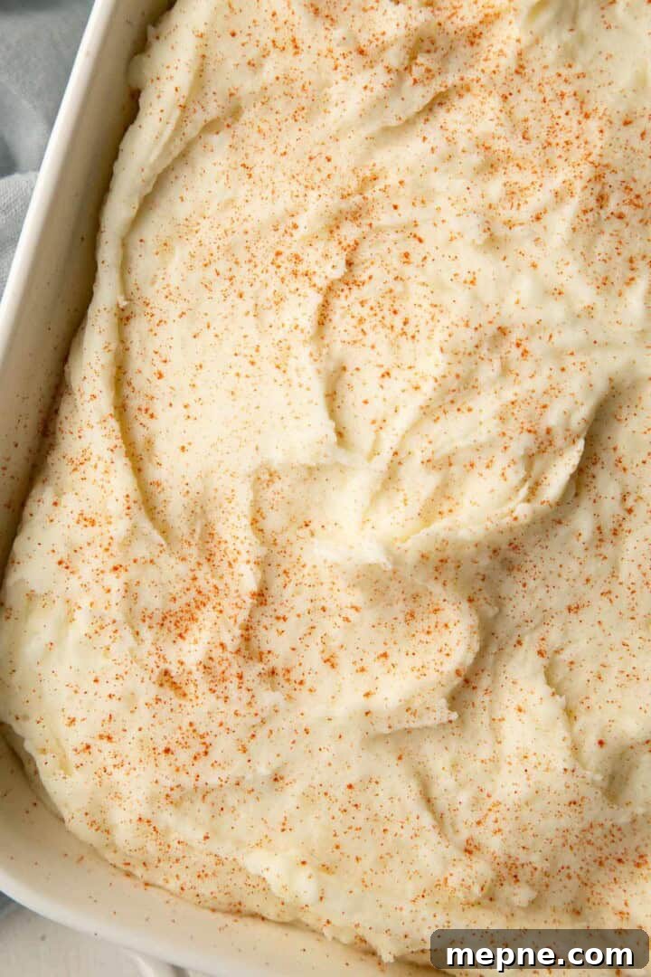 mashed potatoes in a casserole dish, topped with paprika.