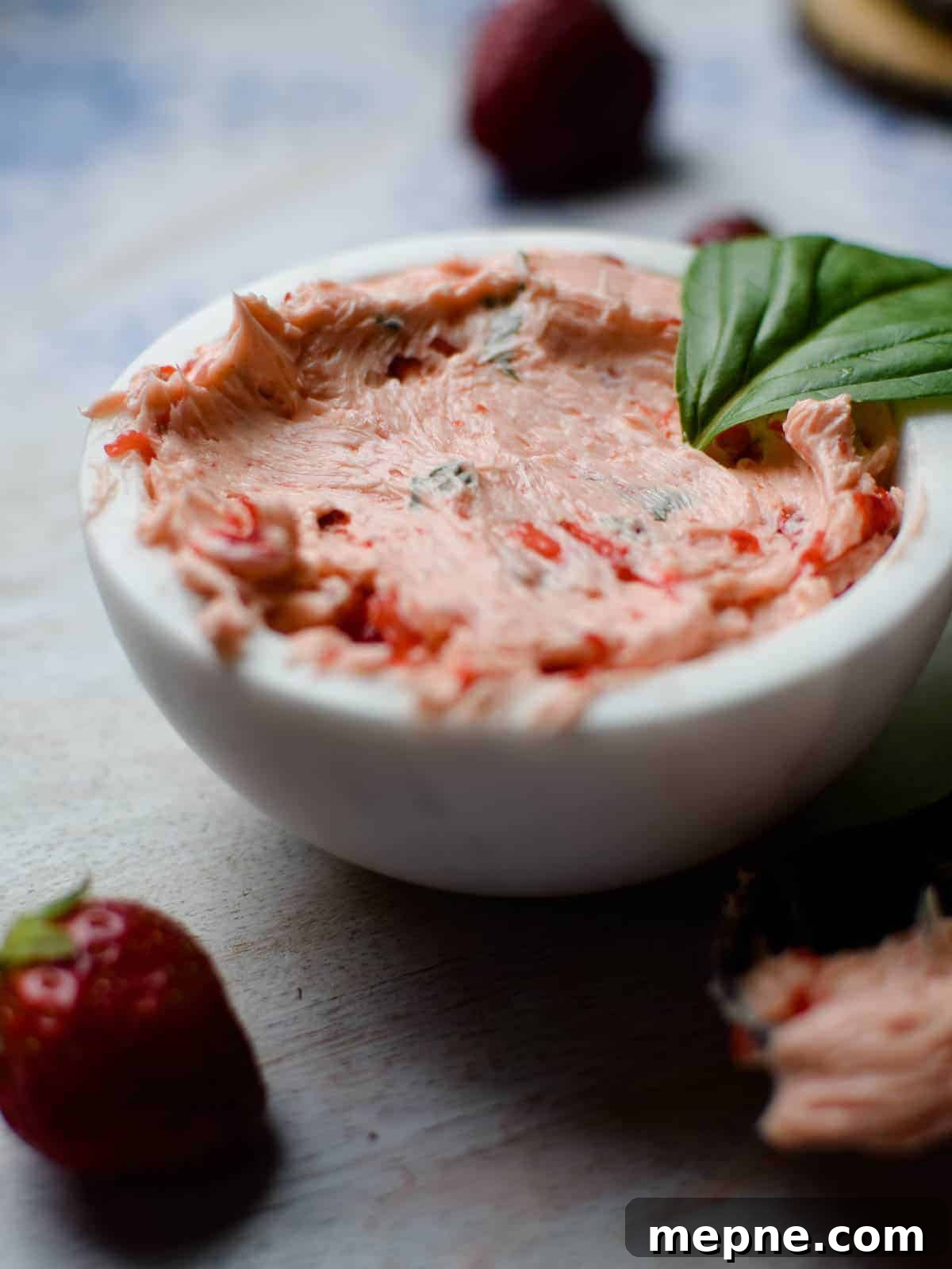 Whipped Strawberry Butter with Fresh Basil Recipe 3 Close-up of whipped strawberry and basil butter in a white bowl.