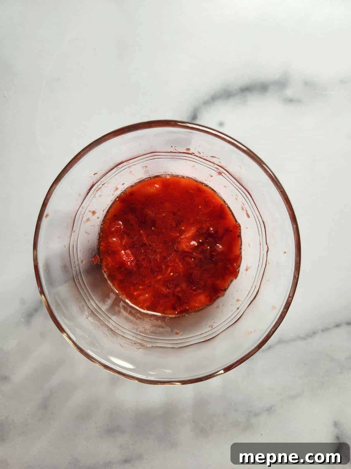 Whipped Strawberry Butter with Fresh Basil Recipe 5 Clear bowl of mashed strawberries.