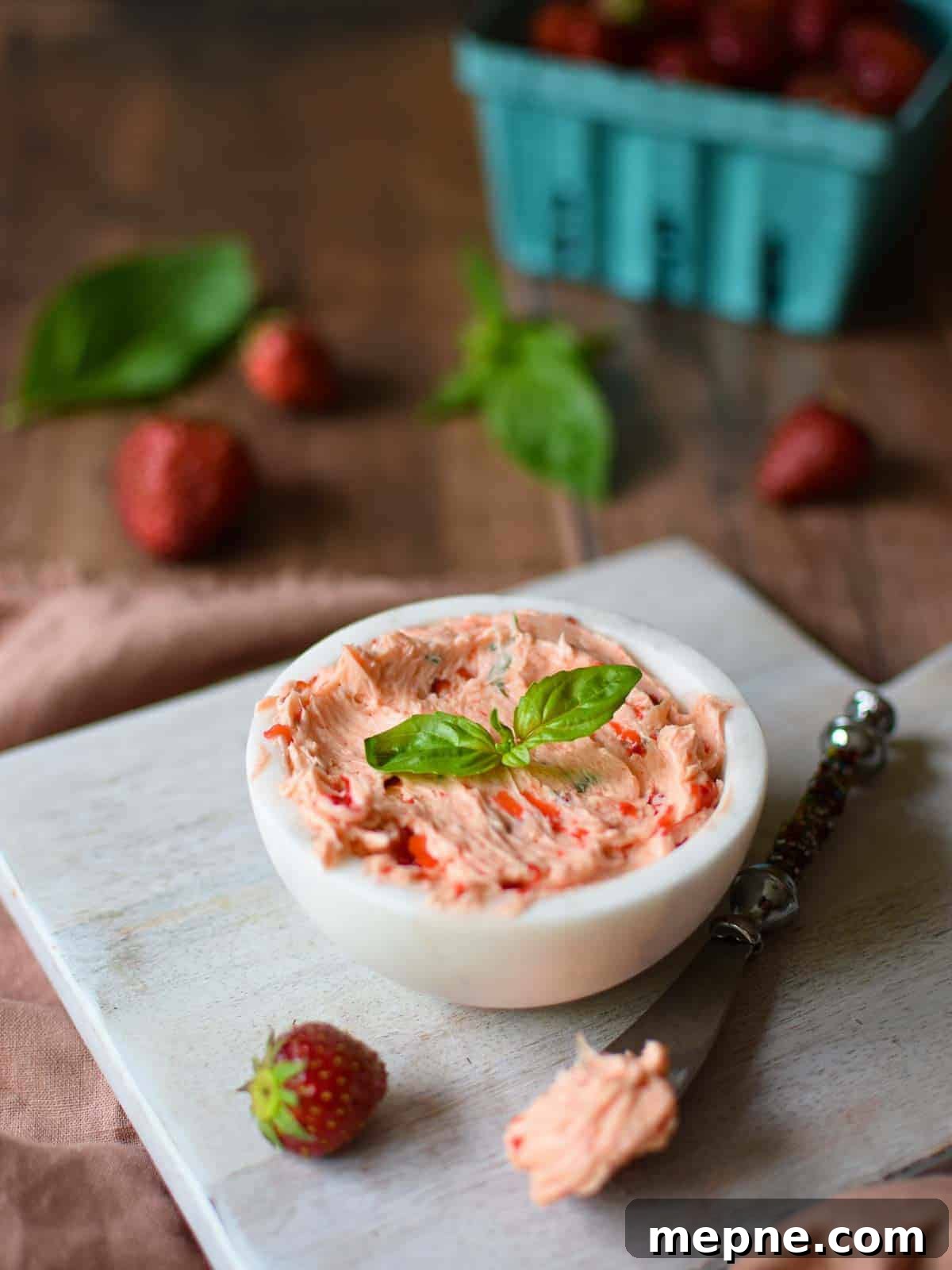 Whipped Strawberry Butter with Fresh Basil Recipe 8 Whipped strawberry butter in a white bowl on a wooden background.