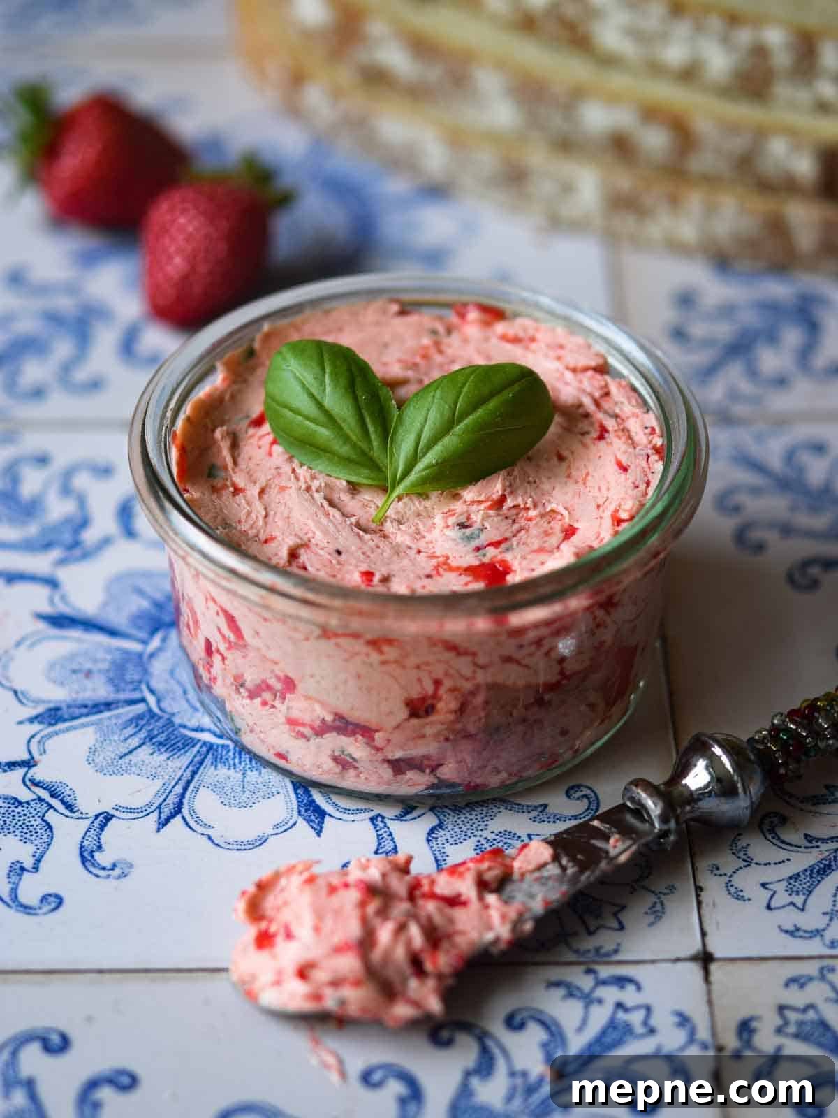 Whipped Strawberry Butter with Fresh Basil Recipe 9 Whipped strawberry basil butter in a glass jar on a tile background.