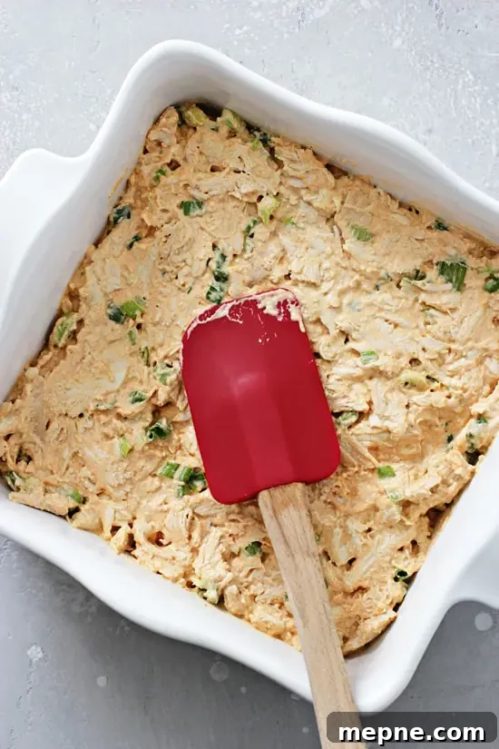 Unbaked dairy free buffalo chicken dip spread in a baking dish before going into the oven. Unbaked dip spread in a baking dish.