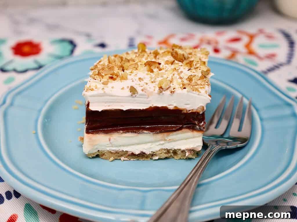 a slice of four layer delight on a blue plate with a fork beside it