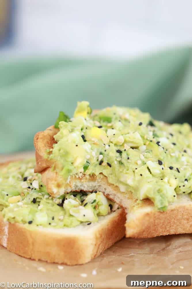 close up of avocado egg salad toast on brown parchment paper with a bite taken