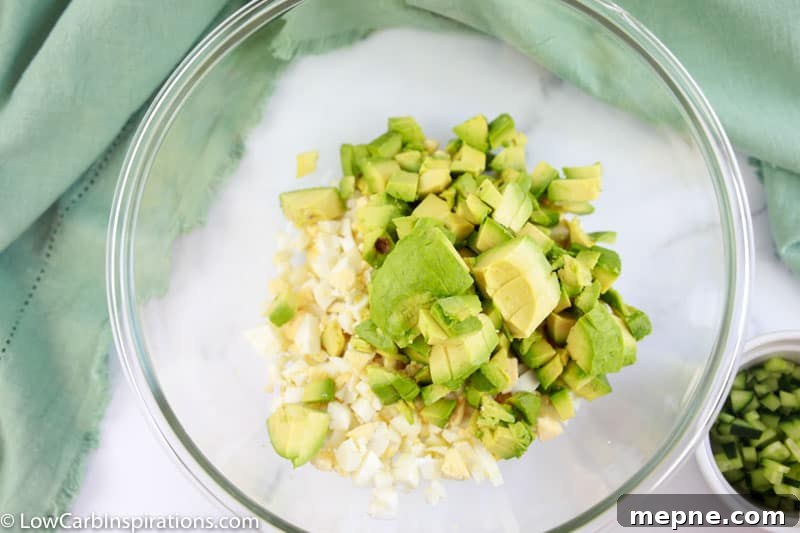 diced eggs and avocado in a clear mixing bowl on a table