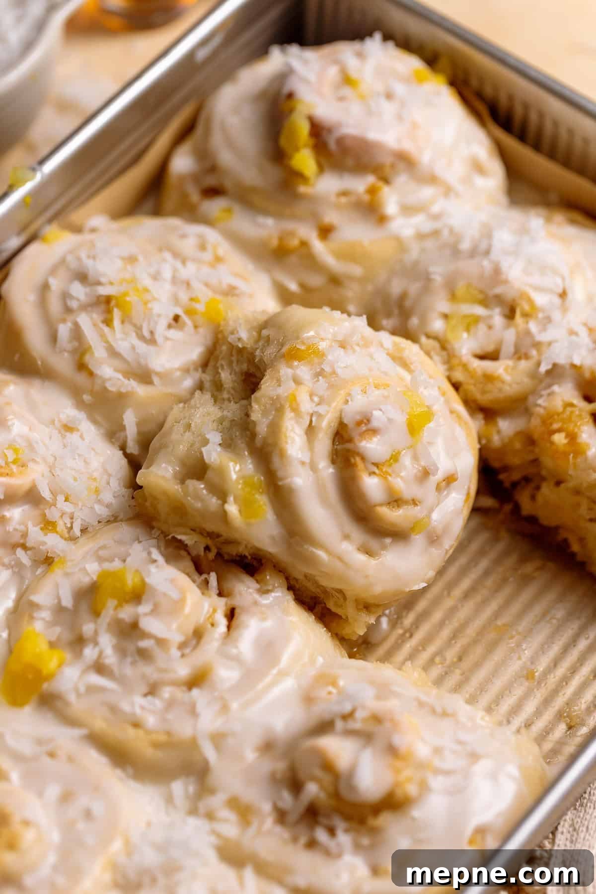 Tropical Pina Colada Cinnamon Rolls with Coconut Rum Icing 11 Pineapple coconut rolls in a baking pan.