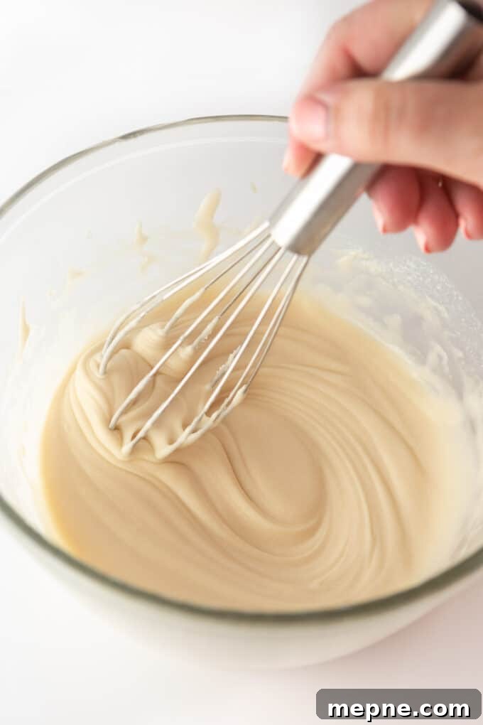 Homemade Cream Cheese Icing for Cinnamon Rolls 4 Pouring glaze over cinnamon rolls