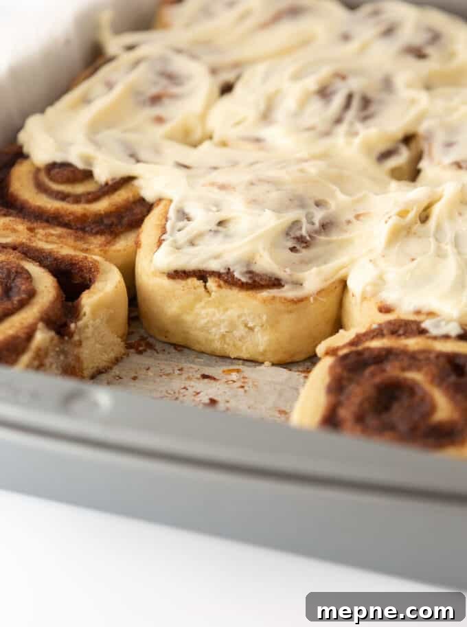 Cream Cheese Frosting Recipe for Cinnamon Rolls 2 Close-up of cinnamon rolls in a baking pan topped with generous swirls of cream cheese frosting