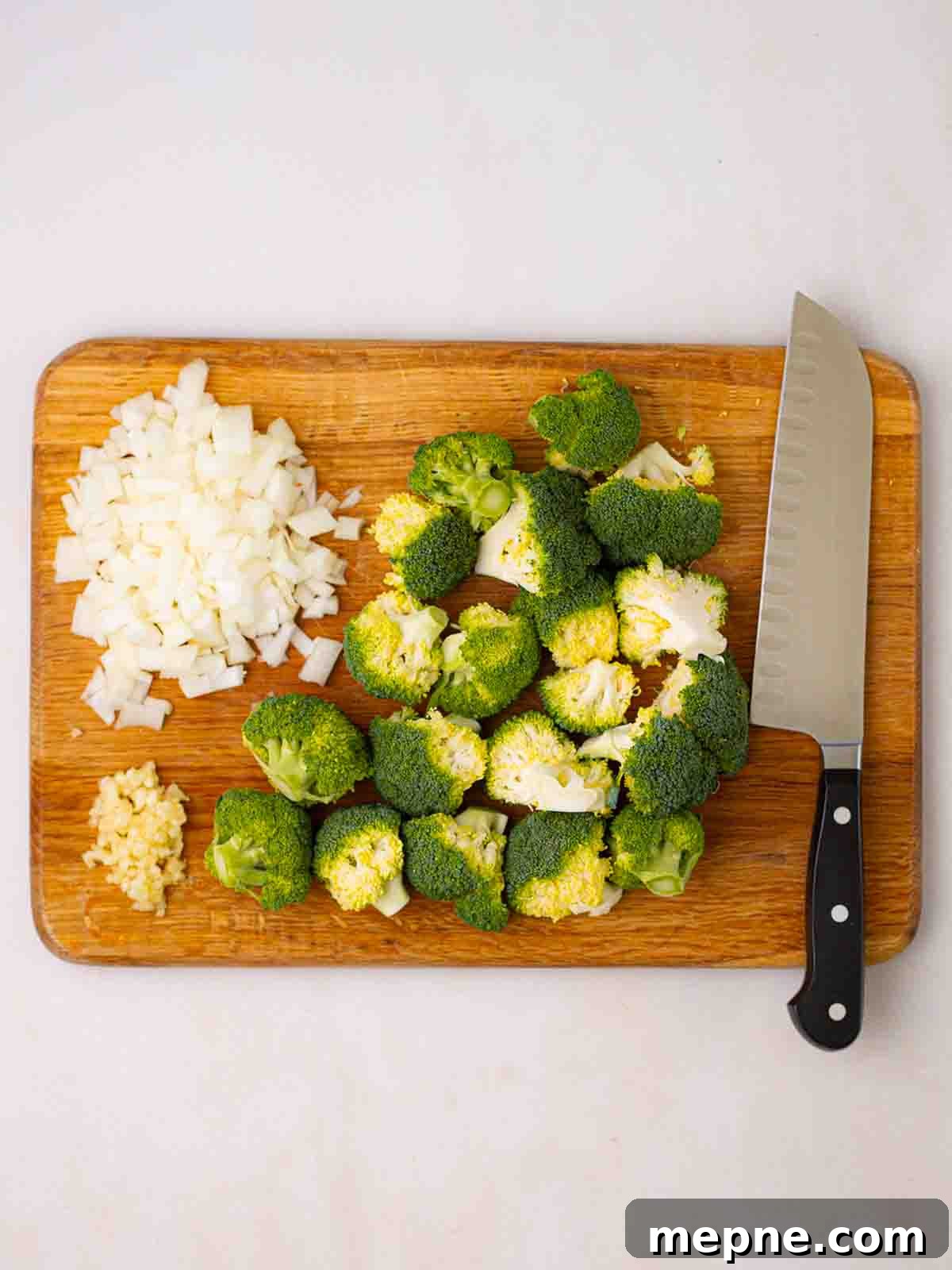 Creamy Broccoli and Stilton Soup Recipe 4 A chopping board with a knife, chopped up broccoli and onion ready to make Broccoli and Stilton Soup.