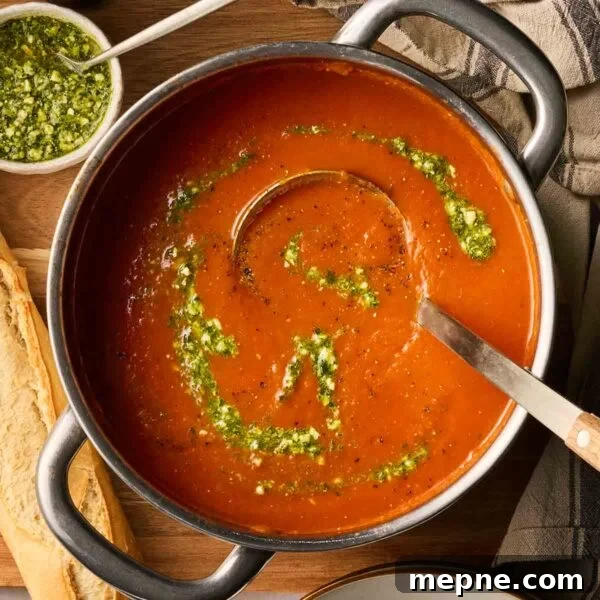 Creamy Broccoli and Stilton Soup Recipe 10 A close up of a big pan of tomato soup with green pesto on top, ready to serve into bowls.