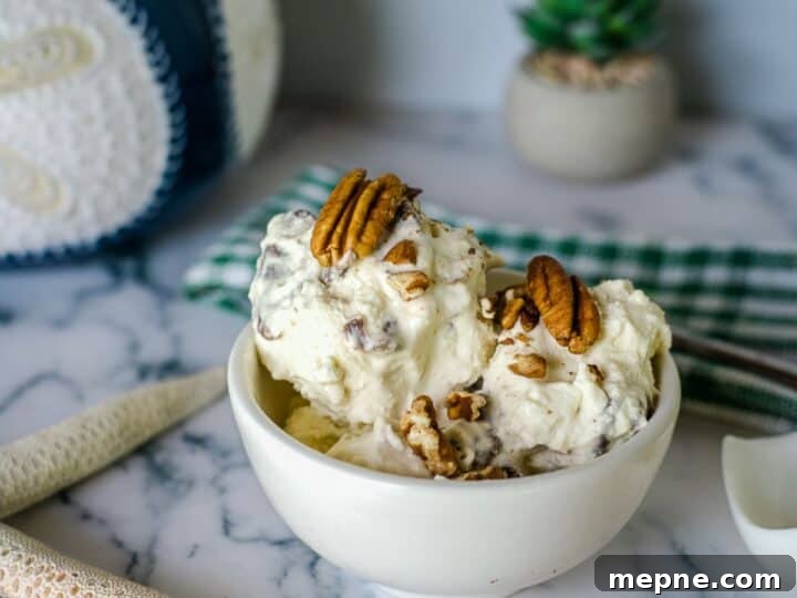 25 Low Carb Ice Cream Recipes for Creamy Keto Desserts 15 A bowl of keto butter pecan ice cream is placed on a marble table, topped with whole pecans. The background features a green and white cloth, a plant, a decorative object, and two starfish ornaments.