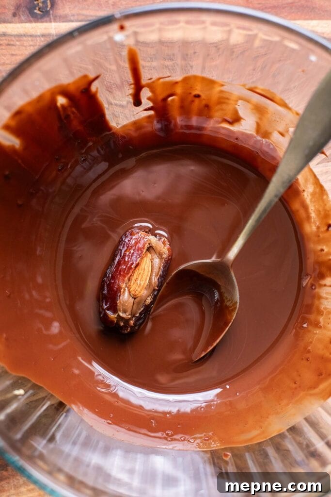 Chocolate-Stuffed Medjool Dates with Nut Butter 8 A peanut butter stuffed date shown being rolled in melted chocolate.